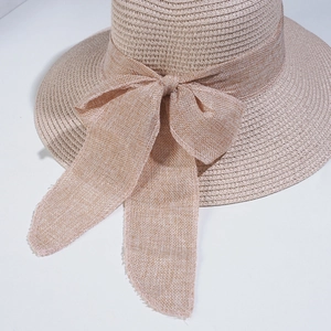 Close-up of khaki straw hat featuring a detailed woven texture and large fabric bow