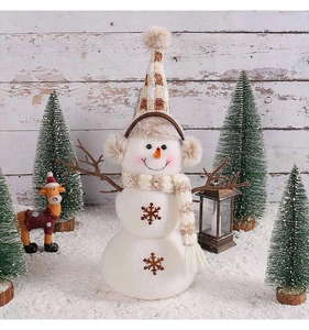 Detailed view of plush snowman figure with brown plaid hat and snowflake embroidery