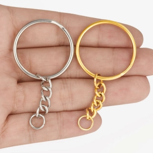 Polished 18K gold and silver stainless steel key rings held in hand for size comparison