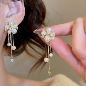 Close-up of elegant pearl and zircon tassel earrings with gold finish on a model