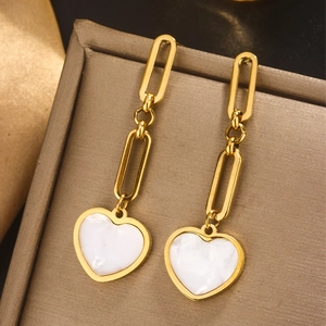 Detail of 18K gold-plated earrings with white heart shell pendants on a jewelry box