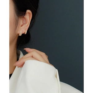 Close-up of gold-plated S925 silver leaf earrings with diamonds on a model's ear