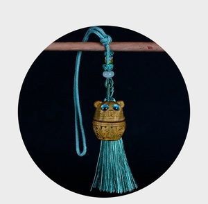 Macro shot of hand-carved wooden cat pendant with blue tassels and ethnic ornaments