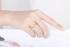 Dettaglio dell'anello a catena sottile in oro con piccole perle indossato sulla mano