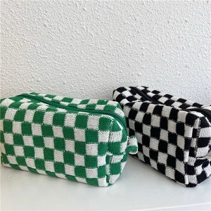 Close-up of knit checkerboard makeup bags in green and black with top zippers