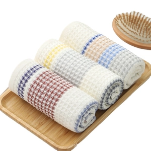 Three-piece waffle weave cotton towel set with colorful stripes on a wooden tray