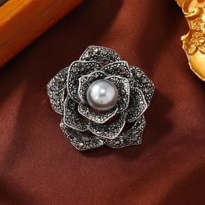 Vintage rose brooch with dark rhinestones and grey pearl on dark satin background
