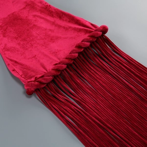 Detailed view of red velvet texture and hand-woven tassel fringe on an elegant dress