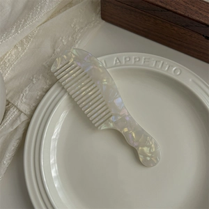 Macro detail of large wide-tooth acetate hair comb with white pearlescent finish