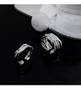 Detail of irregular liquid metal rings with a silver finish on black mirror surface