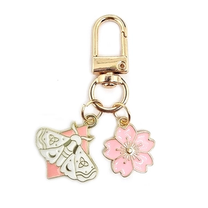 Detail of gold keychain with white butterfly and pink cherry blossom enamel charms