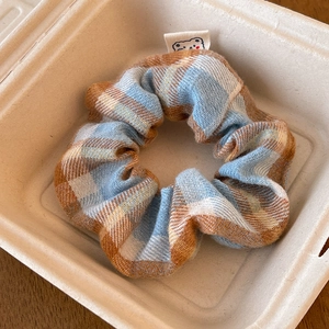 Close-up of plaid scrunchie with cute bear label on soft fabric and inner elastic band