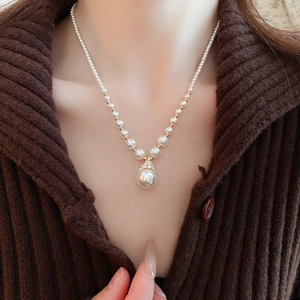Gros plan du collier de perles avec pendentif plaqué or sur mannequin en pull marron