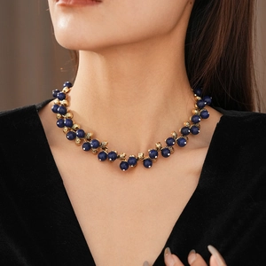Detail of vintage golden necklace with navy blue beads on a black V-neck top