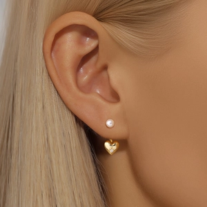 Close-up of elegant gold heart earrings with pearl stud and tiny central diamond
