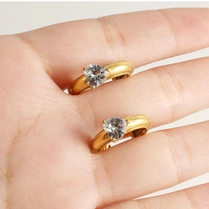 Close-up of gold-plated C-shaped stainless steel earrings with heart-shaped crystal detail
