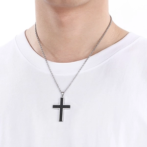 Close-up of a men's black stainless steel cross pendant with silver edges on a model