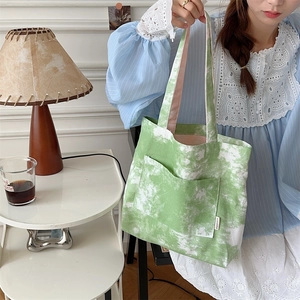 Dettaglio della borsa tote in tela tie-dye verde e bianca con tasca esterna frontale