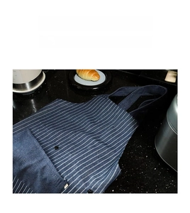 Detail of blue striped chef apron showing durable canvas fabric and large front pocket
