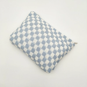 Close-up of blue and white checkered knit pouch featuring woven texture and silver zipper