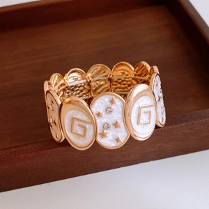 Detail of vintage gold bracelet with white enamel oval panels and star crystal accents