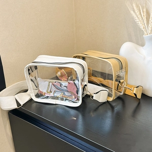 Close-up of transparent PVC crossbody bags with wide fabric straps and decorative silk scarves