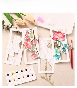 Close-up of 12-color watercolor paint palette with floral hollowed bookmarks and brush