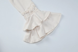 Detailed view of elegant bell sleeves with lace trim on a cream-colored V-neck dress