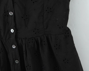 Détail de la broderie anglaise noire avec des boutons nacrés élégants sur la robe