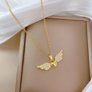 Luxurious gold winged heart necklace with clear crystals on a beige jewelry display