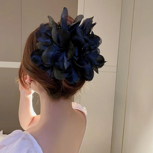 Gros plan sur une grande pince à cheveux fleur en maille noire sur un modèle
