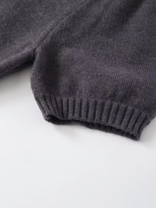 Vue détaillée de la texture du tricot gris foncé avec finitions de poignets côtelés