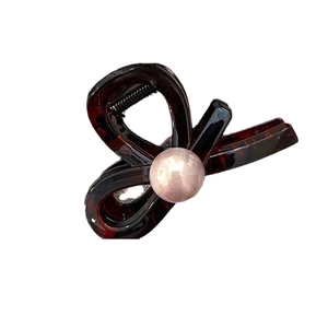 Brown amber patterned bow hair claw clip with pink pearl accent on white background