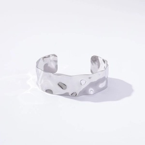 Detailed close-up of a silver irregular textured wide open cuff bangle on white background
