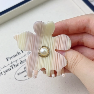 Detailed macro view of acetate floral hair claw with pearl accent and pink gradient stripes