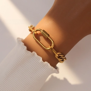 Close-up of dual-tone Cuban chain bracelet with 18k gold carabiner clasp on wrist
