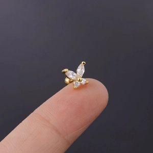 Detail of gold butterfly ear stud with zircon wings held by fingers for scale