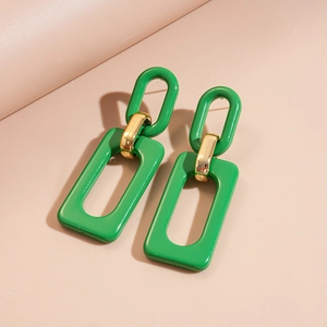 Detail of green acrylic geometric earrings with polished gold metal connectors