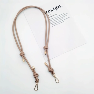 Detail view of beige leather shoulder strap with gold lobster clasps and decorative knots