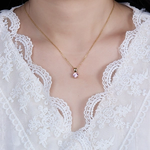 Detail of a gold 925 sterling silver necklace with a round pink zircon pendant on a model