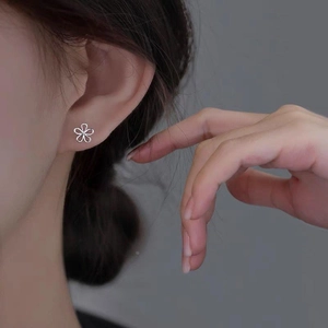 Close-up of S925 sterling silver hollow flower stud earring with center stone on ear