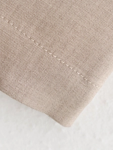 Detailed macro view of light beige fabric texture with precise stitching on jacket suit