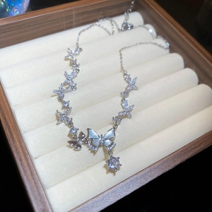 Detail view of silver butterfly pendant with zircon and pearl in a wooden jewelry box