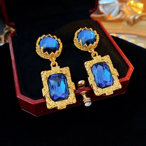 Boucles d'oreilles vintage dorées avec gemme bleu foncé dans un écrin rouge