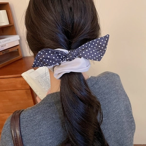 Close-up of a blue polka dot bow scrunchie on a ponytail with a cozy vintage background