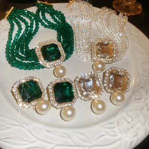 Detail of square emerald and clear crystal multi-strand pearl choker necklace and earrings