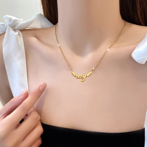 Collana minimalista in acciaio al titanio dorato con ciondolo ali e baby indossata da modella