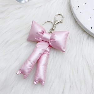 Detailed macro view of a pink satin stuffed bow keychain with a silver metal clasp