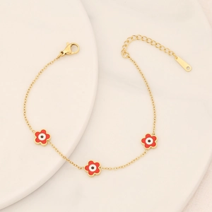 Golden stainless steel flower bracelet with colorful evil eye charms on ceramic tray