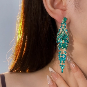 Detail of luxury emerald water-drop tassel earrings with gold-toned metal and green crystals